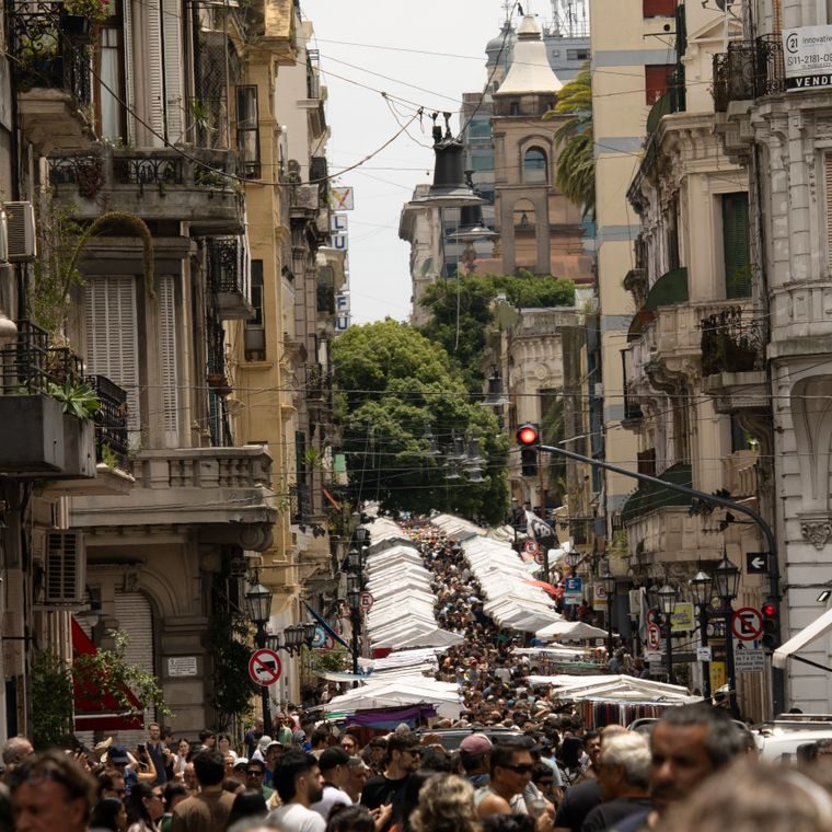 Rua de San Telmo entre prédios antigos, com barracas brancas e uma multidão na feira de domingo
