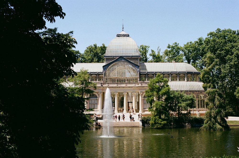 Palácio de Cristal no Parque do Retiro, com uma fonte no lago e árvores ao redor