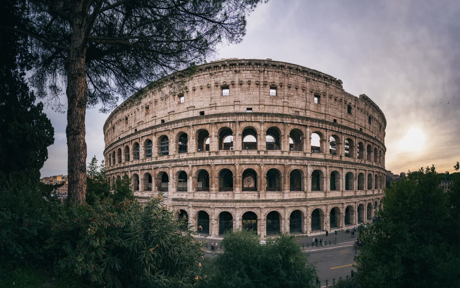 Coliseu de Roma ao pôr do sol, emoldurado por árvores