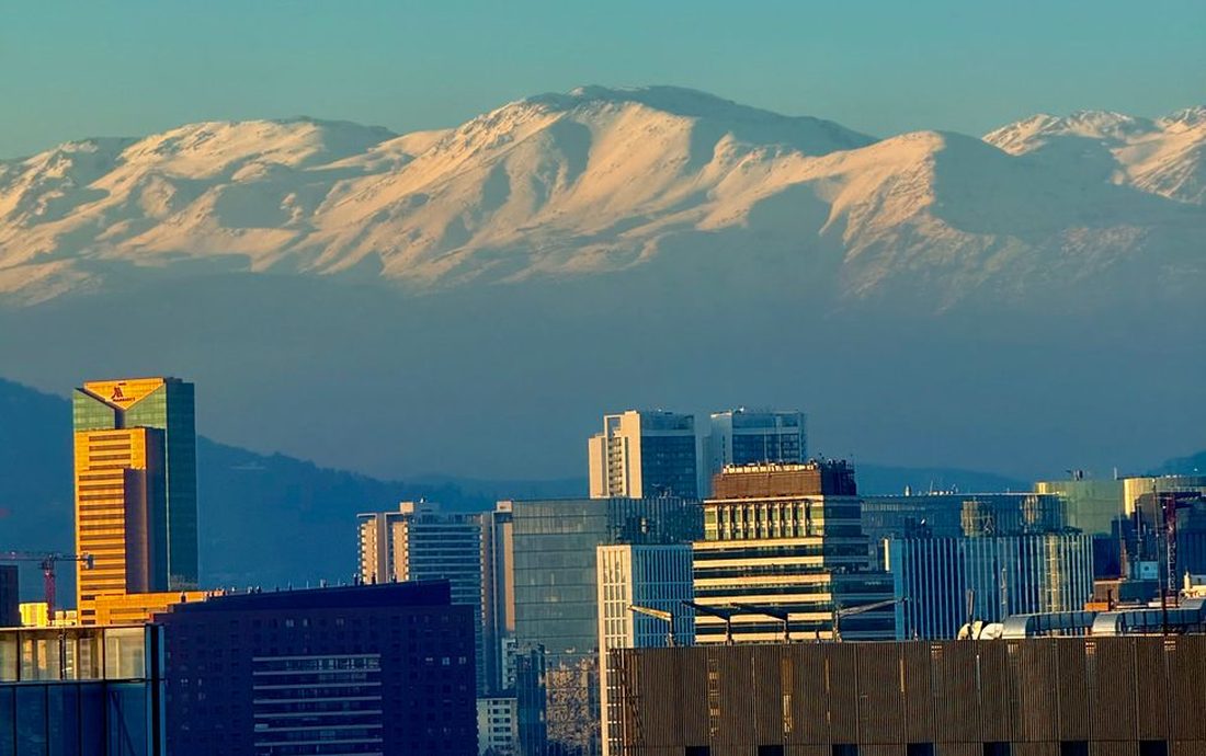 Prédios de Santiago com a Cordilheira dos Andes nevada ao fundo, sob um céu azul