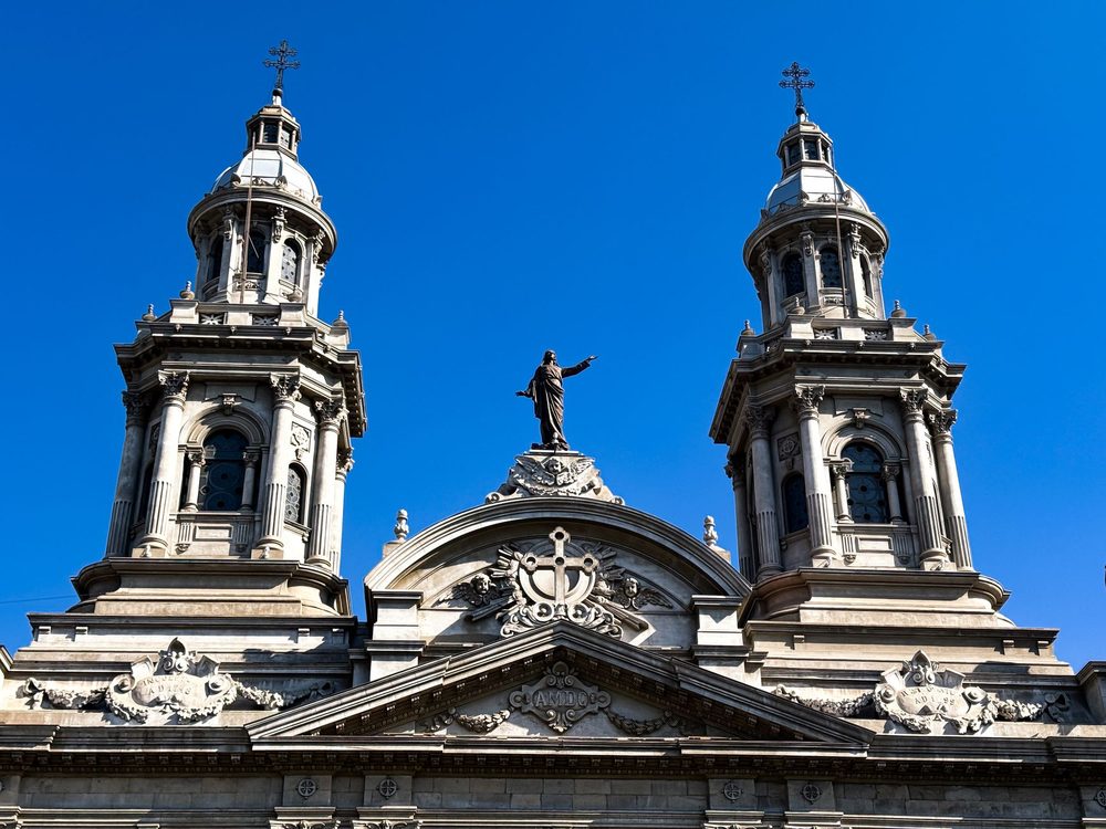 Torres da Catedral Metropolitana de Santiago, com a estátua no alto da fachada, sob céu azul
