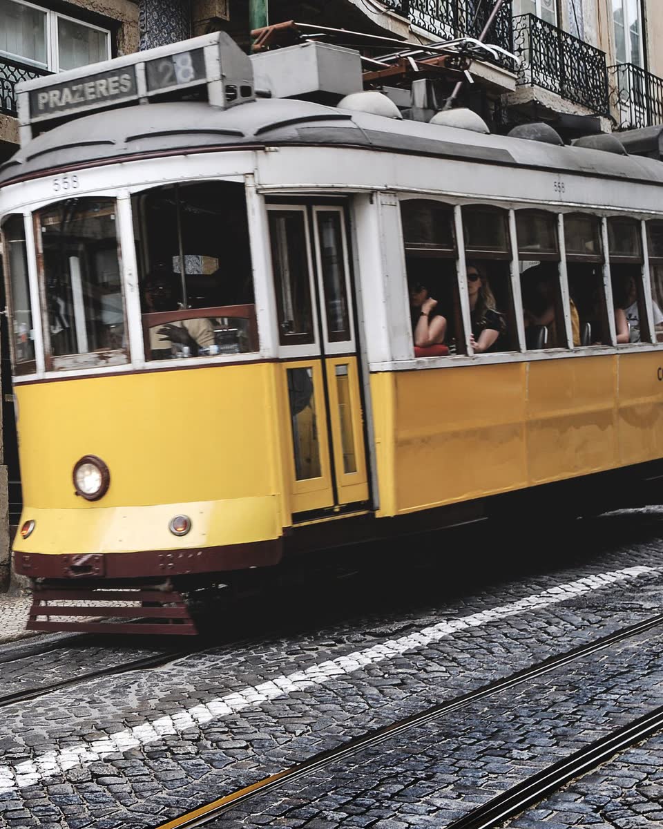 Elétrico amarelo numa rua de pedras de Lisboa