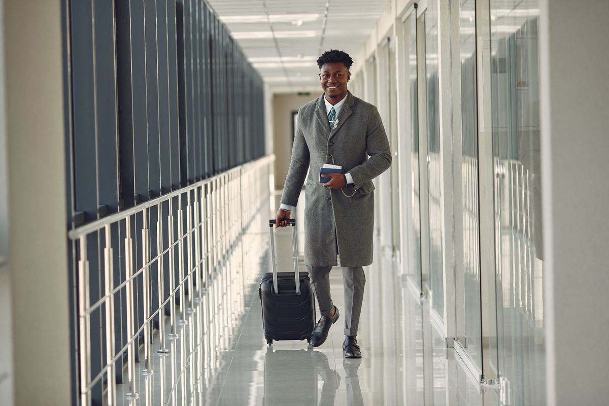 Passageiro caminhando com mala no aeroporto, ilustrando a viagem gerada pela sua indicação